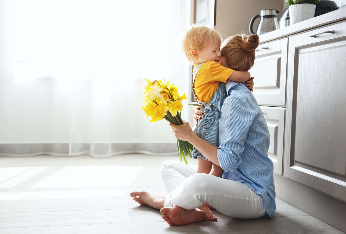 toddler hugging mother on kitchen floor